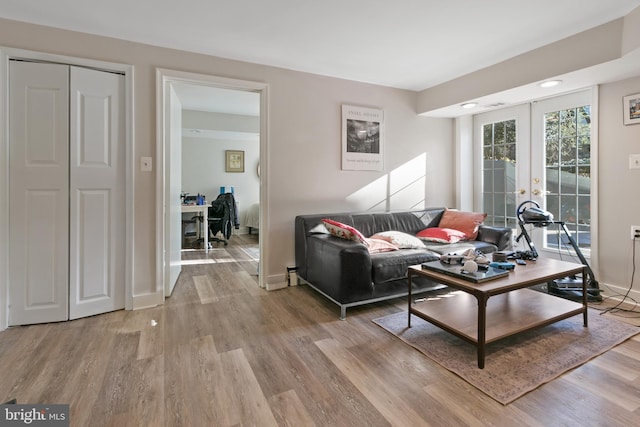 living area featuring french doors, baseboards, and light wood-style floors