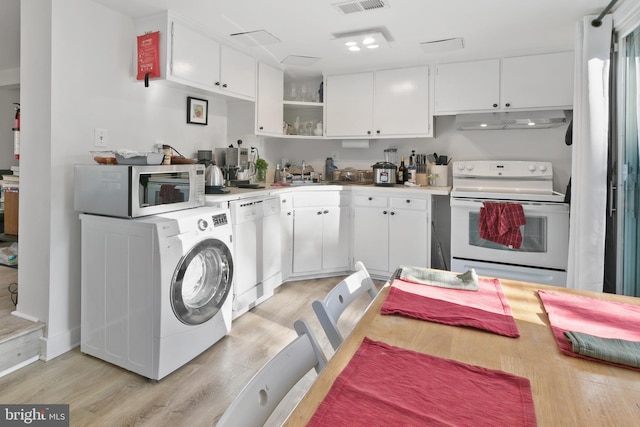 kitchen featuring under cabinet range hood, white cabinetry, white appliances, light wood-style floors, and washer / dryer