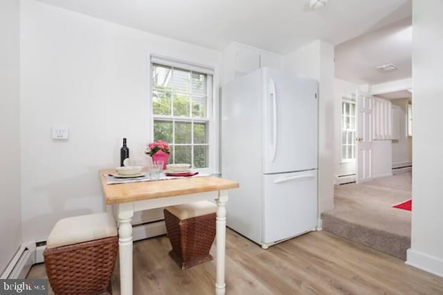 dining area featuring a baseboard heating unit, light wood finished floors, and a baseboard radiator