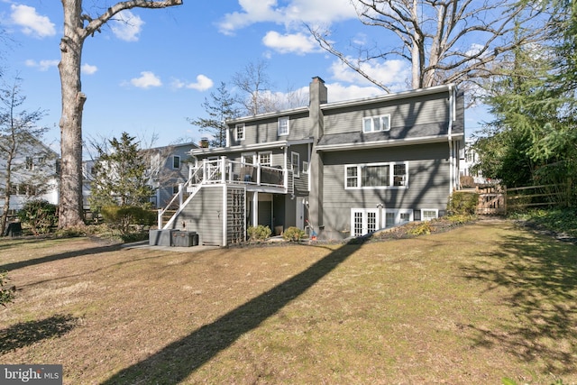 rear view of property featuring stairs, a wooden deck, a lawn, and a chimney