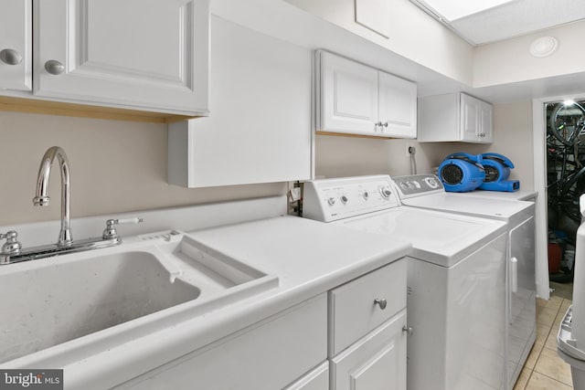 washroom featuring light tile patterned floors, cabinet space, independent washer and dryer, and a sink