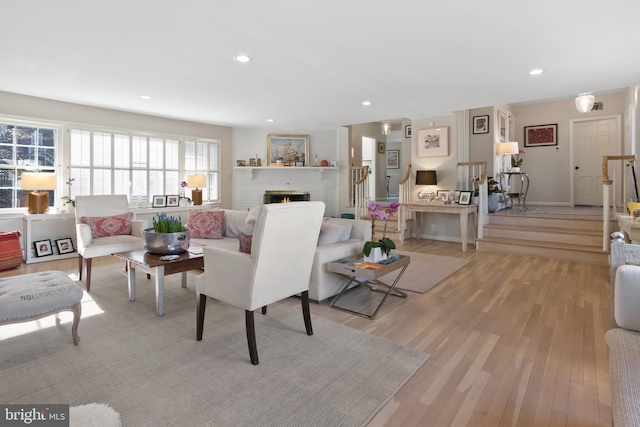 living room featuring recessed lighting, a fireplace, stairs, and light wood finished floors