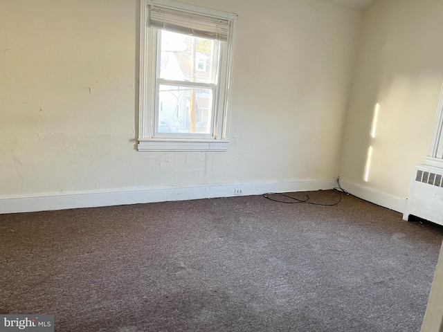 carpeted spare room featuring baseboards and radiator