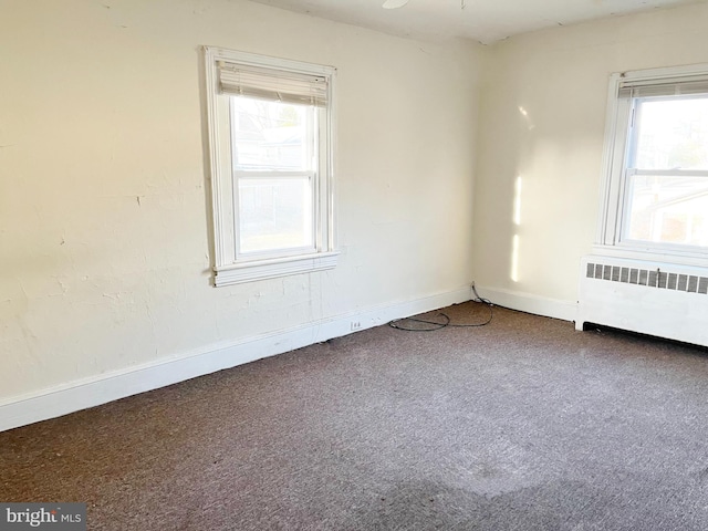 carpeted empty room with radiator and baseboards