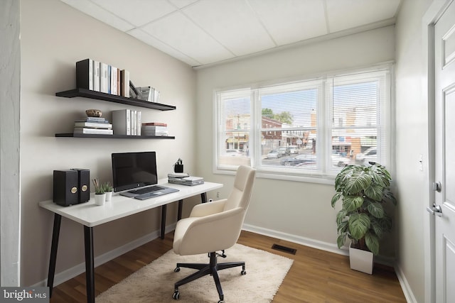 office with visible vents, a paneled ceiling, baseboards, and wood finished floors