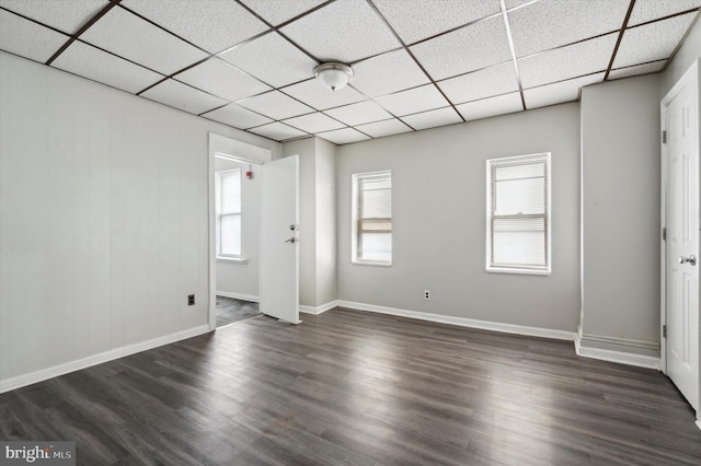 unfurnished room featuring dark wood-style floors, baseboards, and a drop ceiling