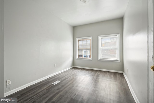 empty room with visible vents, baseboards, and dark wood-style flooring