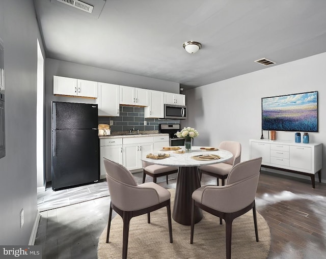 kitchen with visible vents, stainless steel microwave, freestanding refrigerator, decorative backsplash, and stove