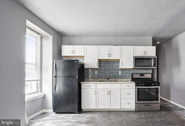 kitchen with a sink, decorative backsplash, a healthy amount of sunlight, and stainless steel appliances