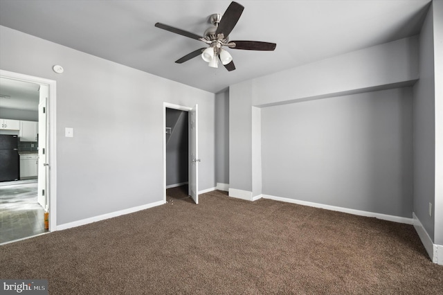 unfurnished bedroom with a closet, baseboards, freestanding refrigerator, and carpet