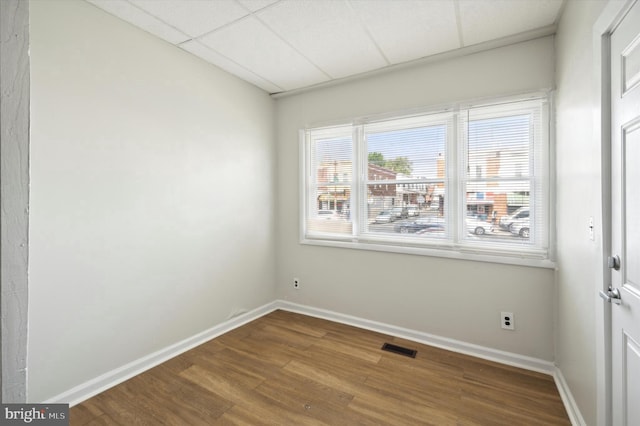 spare room featuring visible vents, a paneled ceiling, baseboards, and wood finished floors