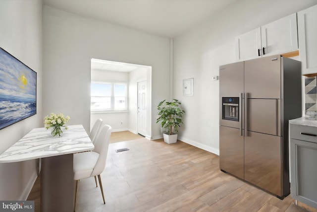 kitchen featuring light wood finished floors, visible vents, baseboards, and stainless steel refrigerator with ice dispenser