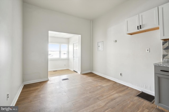 unfurnished dining area featuring light wood finished floors, visible vents, and baseboards