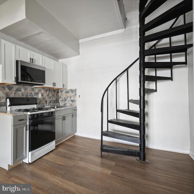 kitchen with range with gas cooktop, stainless steel microwave, dark wood finished floors, and decorative backsplash