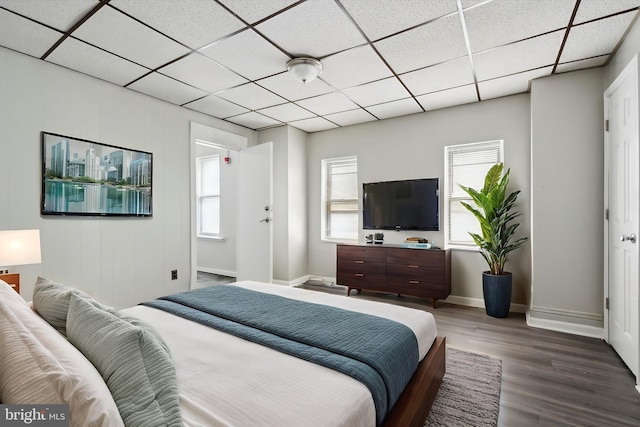 bedroom with wood finished floors, baseboards, and a paneled ceiling