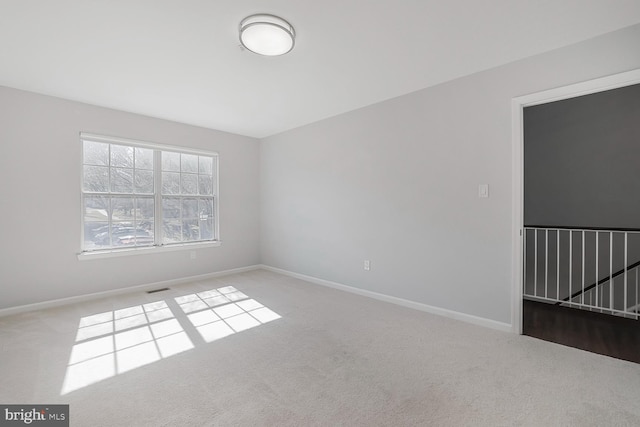 carpeted spare room featuring baseboards and visible vents