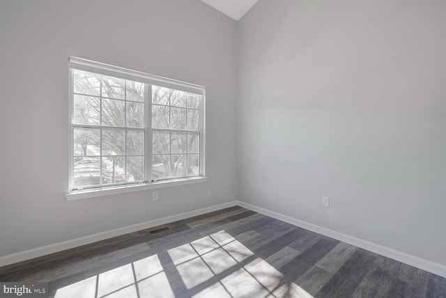 unfurnished room featuring wood finished floors, visible vents, and baseboards