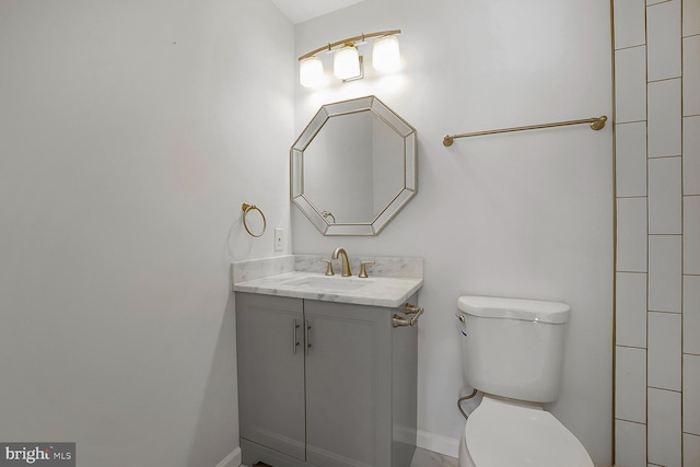 bathroom with vanity, toilet, and baseboards