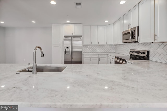 kitchen featuring a sink, stainless steel appliances, light stone countertops, and visible vents