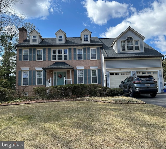 view of front facade with aphalt driveway, an attached garage, brick siding, and a front lawn