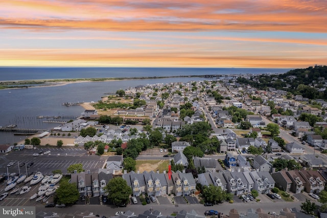 aerial view at dusk featuring a residential view and a water view