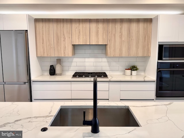 kitchen with modern cabinets, decorative backsplash, and appliances with stainless steel finishes