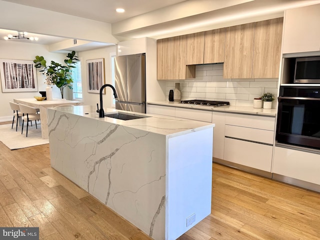 kitchen with modern cabinets, light wood-style floors, appliances with stainless steel finishes, and a sink