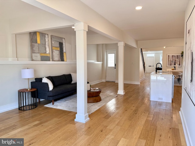 interior space featuring decorative columns, light wood-style floors, and baseboards