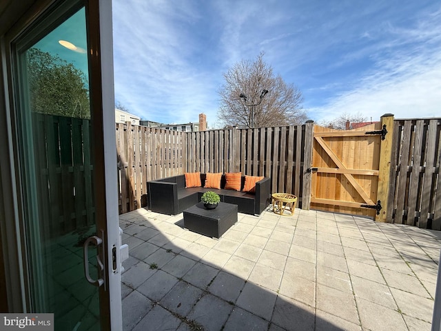 view of patio with an outdoor living space, fence, and a gate