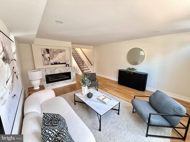 living room featuring stairs, wood finished floors, a fireplace, and baseboards