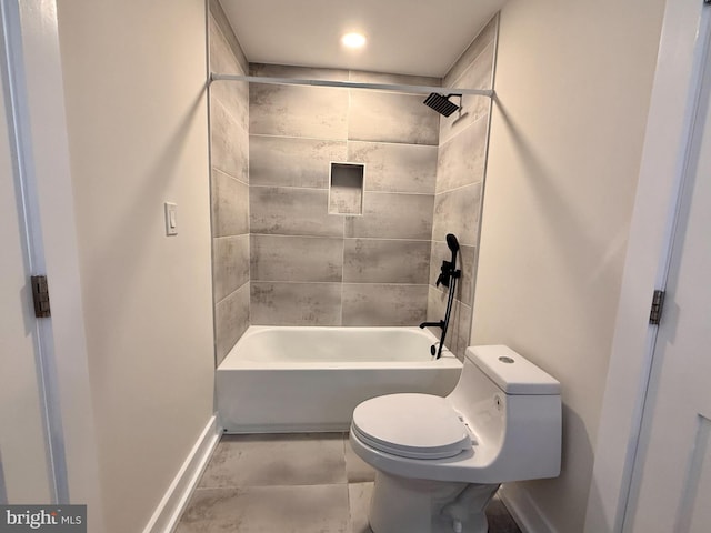 bathroom featuring bathing tub / shower combination, toilet, and baseboards