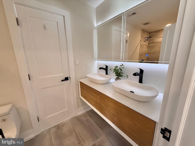 bathroom with a sink, visible vents, wood finished floors, and double vanity