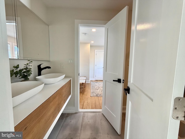 full bathroom featuring double vanity, recessed lighting, wood finished floors, and a sink