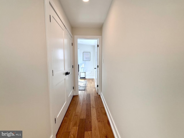 corridor with light wood-type flooring and baseboards