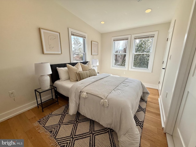 bedroom with recessed lighting, lofted ceiling, light wood-type flooring, and baseboards