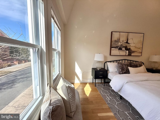 bedroom with lofted ceiling, wood finished floors, and baseboards