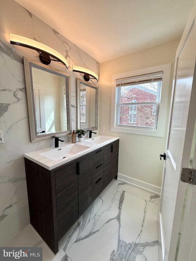 bathroom featuring a sink, baseboards, marble finish floor, and double vanity