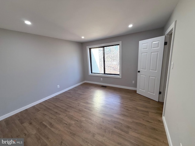 spare room with recessed lighting, baseboards, and dark wood-style flooring