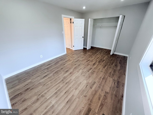 unfurnished bedroom featuring recessed lighting, a closet, baseboards, and wood finished floors