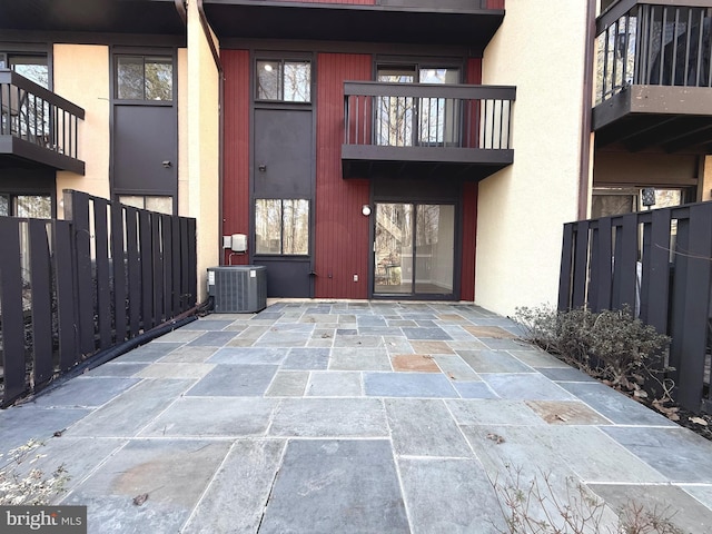 doorway to property with cooling unit, fence, and stucco siding