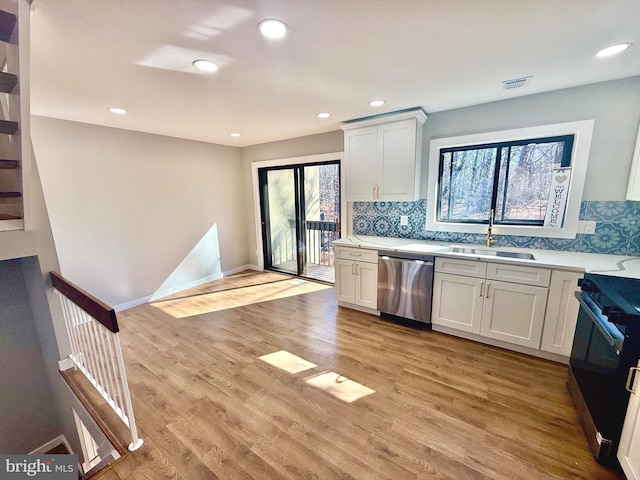 kitchen featuring visible vents, light countertops, range, stainless steel dishwasher, and a sink