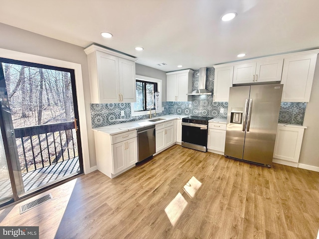 kitchen with visible vents, a sink, stainless steel appliances, light countertops, and wall chimney exhaust hood