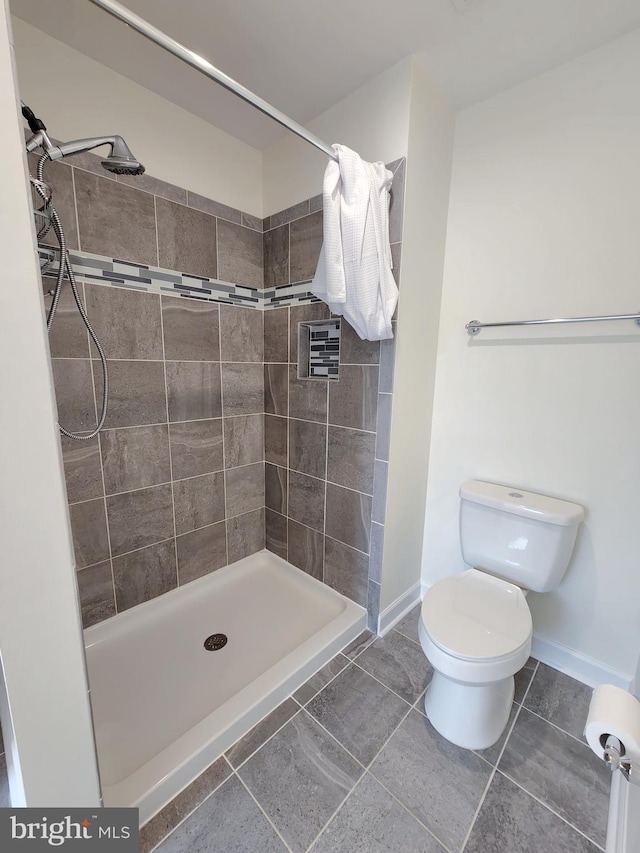 bathroom with a shower stall, toilet, and baseboards