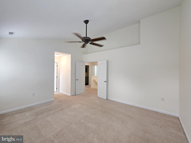 unfurnished bedroom with baseboards, light carpet, visible vents, and vaulted ceiling