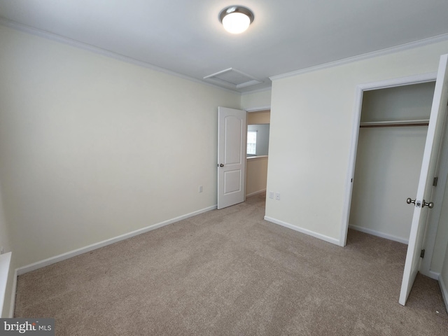 unfurnished bedroom featuring carpet, baseboards, attic access, ornamental molding, and a closet