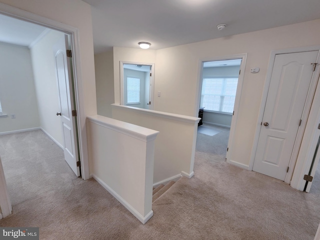 hallway with carpet, an upstairs landing, and baseboards