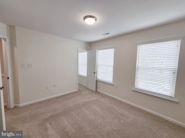 carpeted spare room with visible vents and baseboards