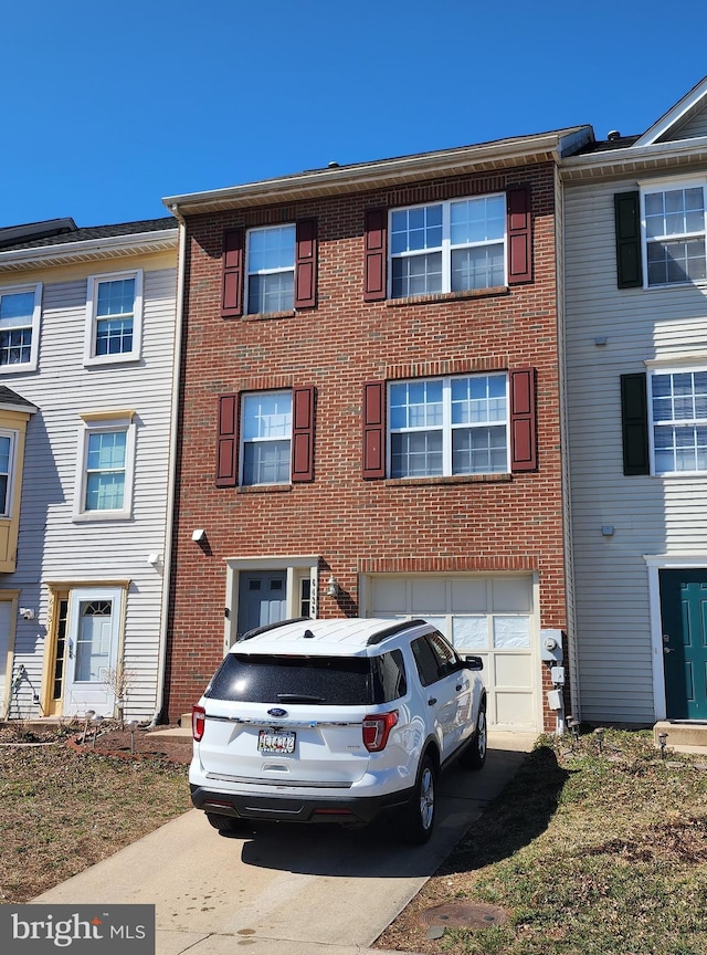 view of property featuring an attached garage, brick siding, and driveway