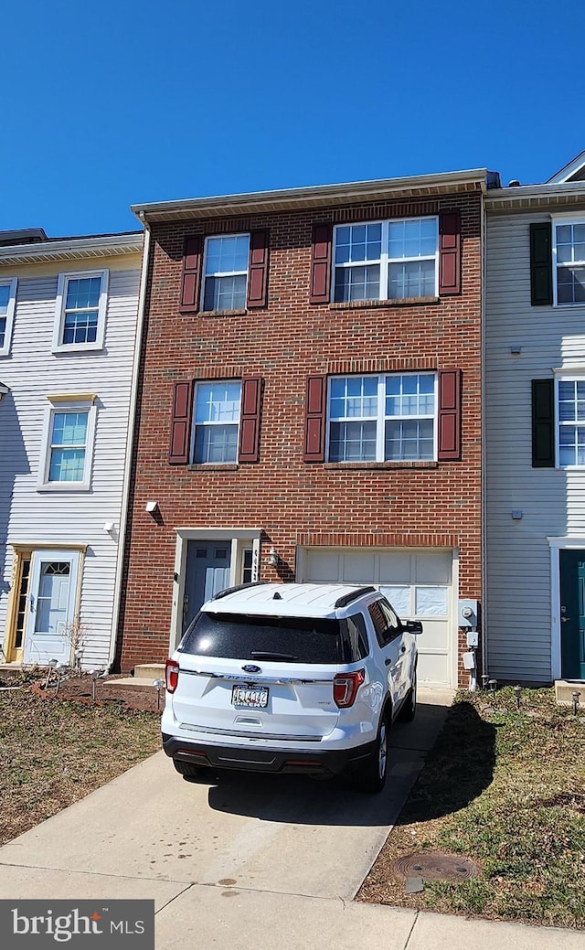 townhome / multi-family property featuring brick siding, driveway, and a garage