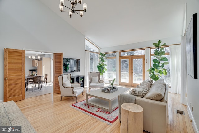 living room with visible vents, high vaulted ceiling, light wood-style flooring, french doors, and a chandelier